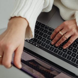 kaboompics_woman-in-white-sweater-gold-rings-jewelry-jeans-laptop-work-29445